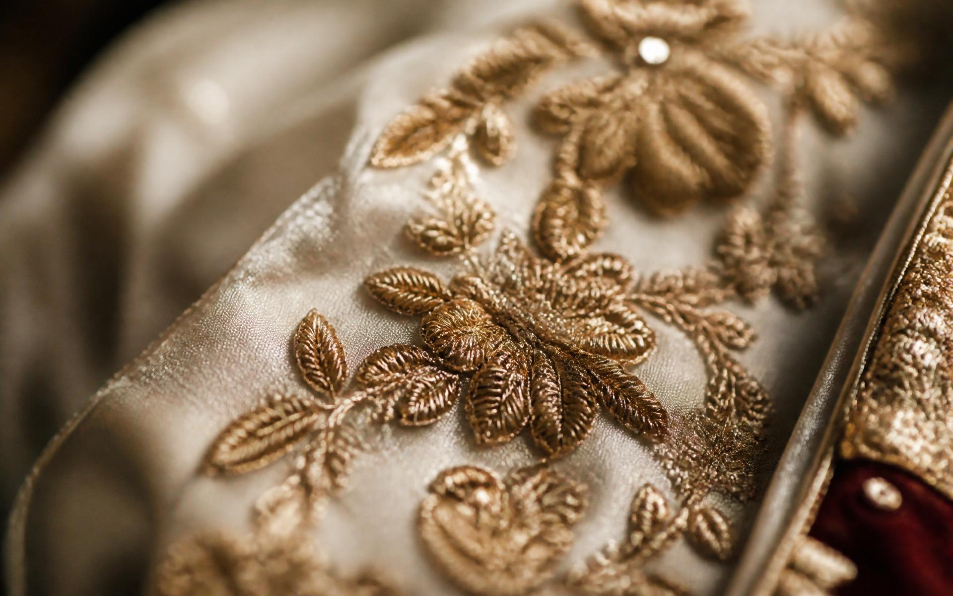 Close-up of intricate gold hand embroidery on ivory silk